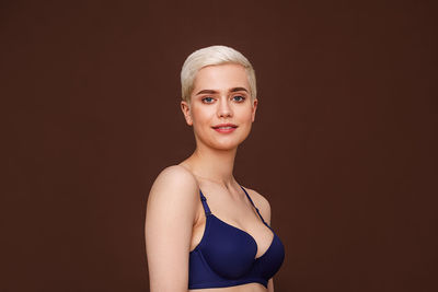 Portrait of young woman standing against black background