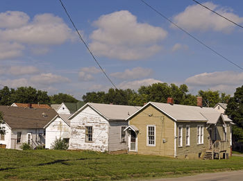 Houses on field against cloudy sky