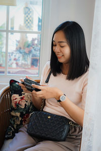 Young woman using phone while sitting at home