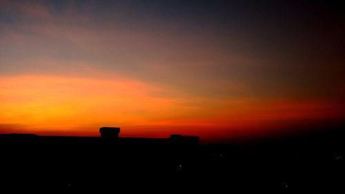 Silhouette buildings against orange sky