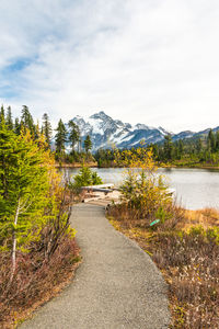 Footpath by lake against sky