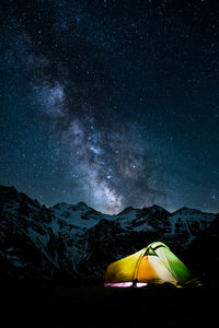 Tent against mountain range at night