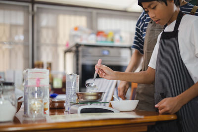 Young boy measuring ingredient for baking in kitchen