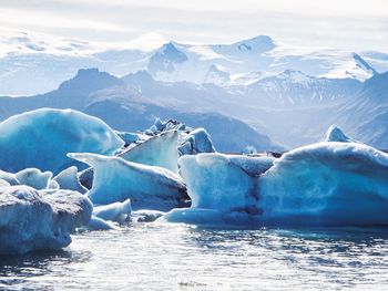 Glacial ice on sea shore against sky