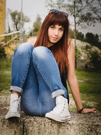 Portrait of woman sitting on retaining wall