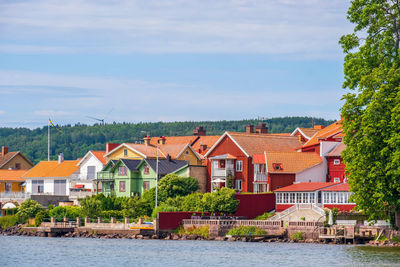 Houses by river and buildings against sky