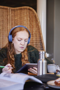 Young woman wearing headphones and studying