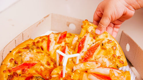 Close-up of hand holding pizza