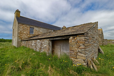 Old house on field against sky