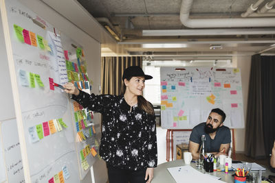 Businesswoman showing whiteboard and explaining colleagues in board room