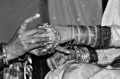 Close-up of bridesmaid helping bride wear bangle