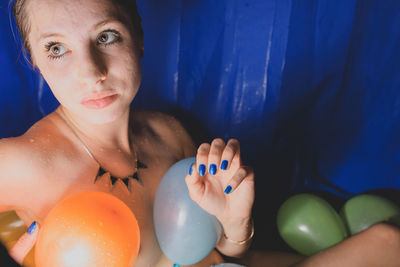 Portrait of woman with colorful balloons at home