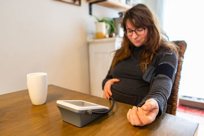 Portrait of smiling woman checking blood pressure at home