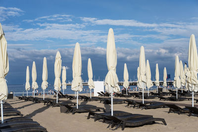 Parasols and lounge chairs at beach against sky