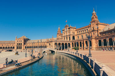 View of canal and buildings against clear blue sky