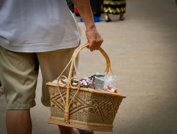 Midsection of man holding basket outdoors