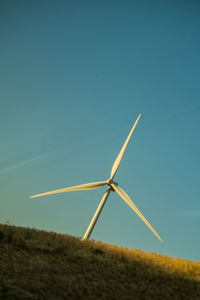 Windmill on field against clear blue sky