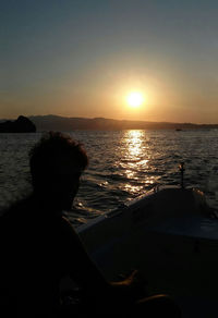 Silhouette man looking at sea against sky during sunset