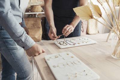 Midsection of male entrepreneurs with bracelets standing by customer in design studio