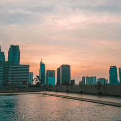 Modern buildings in city against sky during sunset