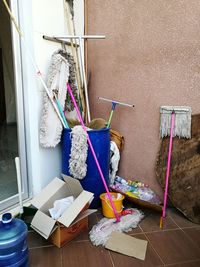 Various mops in container against wall
