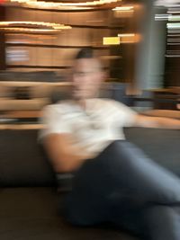 Blurred motion of man sitting at illuminated railroad station