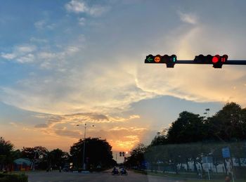 Cars on street against sky during sunset