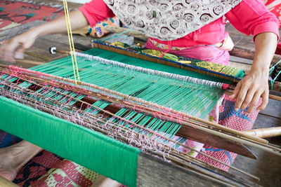 Low section of woman weaving in workshop