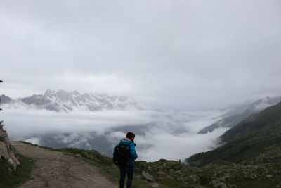 Rear view of man standing on mountain against sky