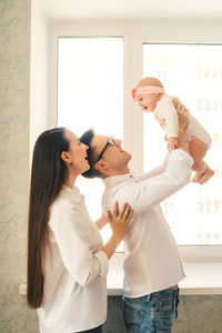 Young couple standing against window