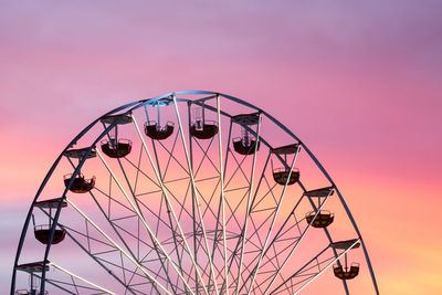 Low angle view of ferris wheel against sky during sunset