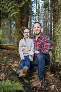 Young father holds his handsome son in the forest.