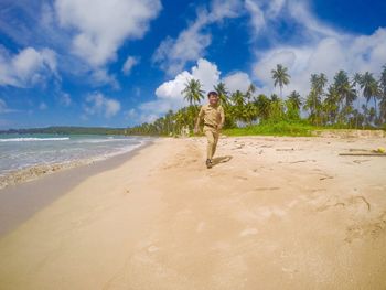 Full length of police man running at beach against sky