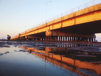 Bridge over river in city against clear sky