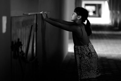 Side view of girl looking over retaining wall in stable