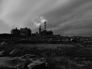 Smoke emitting from chimney on field against sky