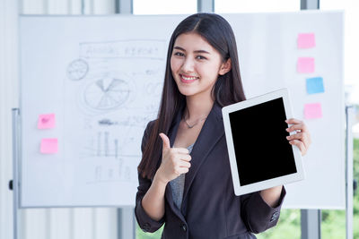 Portrait of a smiling young woman standing against wall