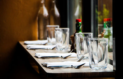 Close-up of drinking glasses with knife and folks arranged on table at restaurant