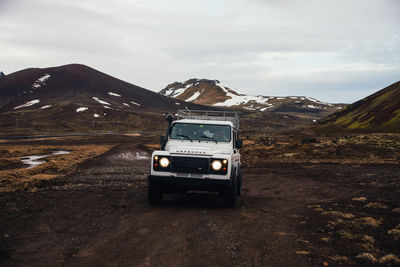 Car on road against mountain range against sky