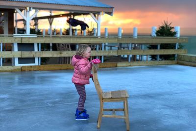 Girl holding chair while ice skating on rink