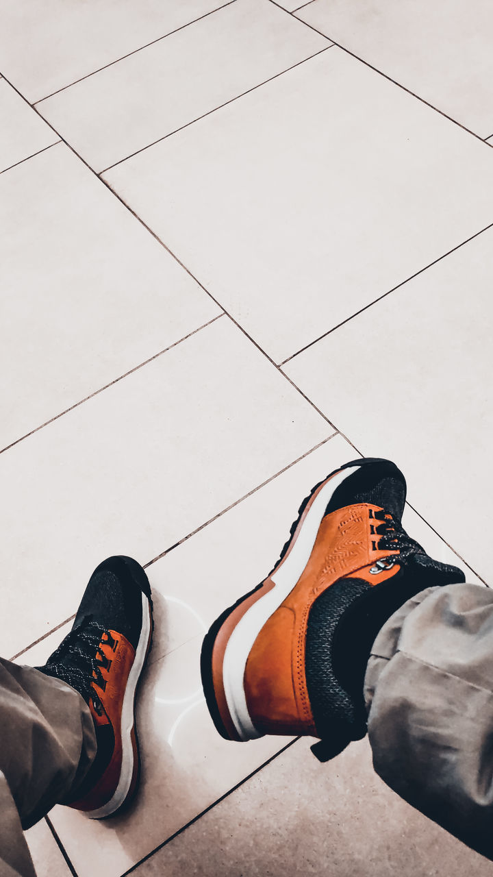 footwear, lifestyles, shoe, low section, adult, human leg, men, one person, sports, flooring, high angle view, black, leisure activity, limb, white, tiled floor, relaxation, human limb, day, exercising, young adult, tile, clothing, casual clothing, outdoors, copy space