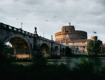 View of arch bridge over river against cloudy sky