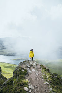 Rear view of person on rock against sky