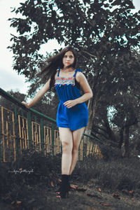 Portrait of young woman standing against trees