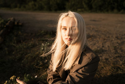 Portrait of beautiful young woman sitting on land in forest