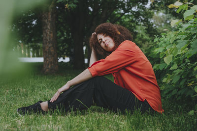 Contemplative young woman sitting on grass at park