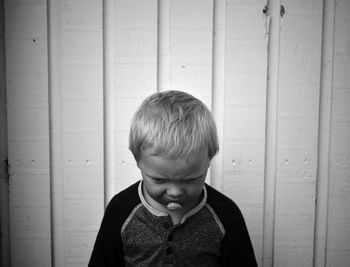 Close-up of boy standing against wooden wall