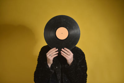 Woman with turntable standing against colored background
