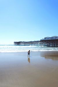 Full length of man on beach against clear blue sky