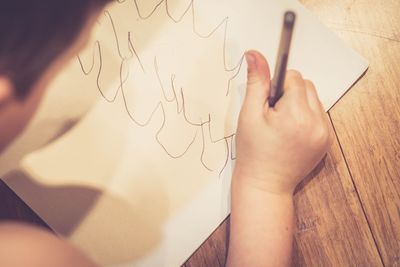 High angle view of boy drawing on paper